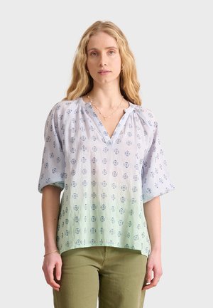 Lichtblauwe blouse met korte mouwen en V-hals, met een bloemenpatroon en subtiele gradient. Gemaakt van zachte, gestructureerde stof.