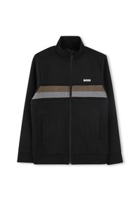Črna zip-up jakna iz mehkega blaga, ki ima črtasto vzorčenje v zlatih in belih odtenkih po prsih ter dve stranski žepi.