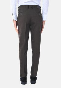 Pantaloni grigi scuri con design aderente, realizzati in cotone, dotati di tasche posteriori e gamba dritta. Abbinati a scarpe nere.