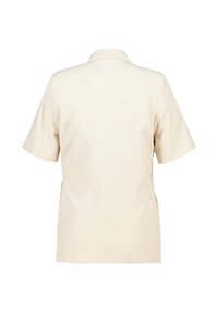 Blouse à manches courtes, de couleur beige clair, avec un col structuré, une texture lisse et des détails de couture au dos pour un ajustement sur mesure.