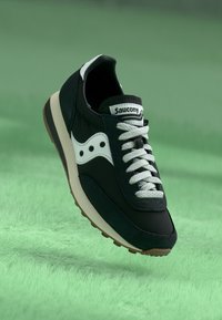 Black and white sneaker with a suede and mesh upper, featuring a rounded toe, white laces, and a neutral rubber sole.
