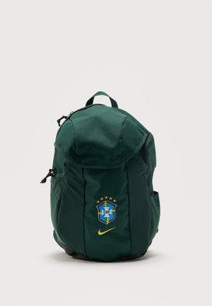Tmavozelený batoh s logom brazílskej futbalovej federácie a žltým Nike znakem vpredu na jednofarebnom pozadí.