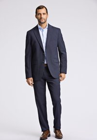 Navy blue garnitur w wzór, z klapami wyłogo, z zapięciem na guziki i dwiema przednimi kieszeniami. Połączony z jasnoniebieską koszulą i brązowym skórzanym obuwiem.