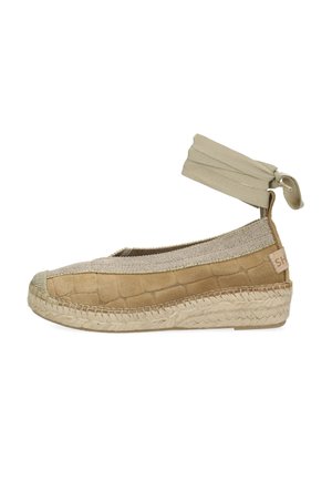 Espadryl z beżową teksturowaną cholewką z zamszu, elastycznym paskiem wokół kostki i plecioną podeszwą z juty. Posiada zaokrąglony nosek i subtelne logo po boku.