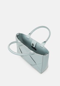 Lyseblå tote bag lavet af syntetisk læder, med to håndtag, klaplukning og et geometrisk paneldesign med kontrasterende syninger.