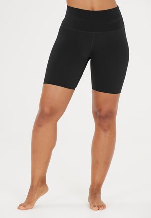 Shorts noir taille haute en tissu extensible. Présentent une texture lisse, un design jusqu'aux genoux et pas de coutures ni de motifs visibles.