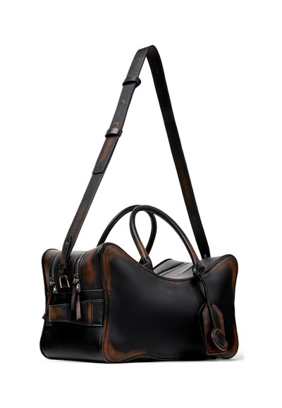 Sac de voyage en cuir noir et marron usé avec poignées doubles, bandoulière ajustable, poches avant zippées et étiquette à bagages attachée.