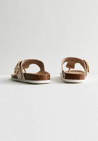 Bruine kurken platform sandalen met witte zolen, voorzien van een lichtgekleurde, verstelbare band en een open achterkant ontwerp. Getextureerde voetbed.