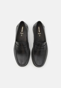 Schwarze Lederloafers mit glatter Oberfläche, die ein doppelte Riemensystem und texturierte Nähte entlang der Sohle aufweisen. Geox-Logo innen sichtbar.