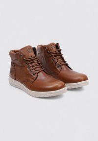 Bottines en cuir marron avec lacets, semelles en caoutchouc blanches, finition texturée et logo sur le côté. Dispose d'un col rembourré pour plus de confort.