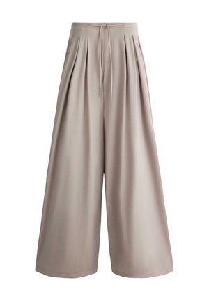 Beżowe spodnie o szerokich nogawkach z plisami i sznurkiem w pasie, charakteryzujące się luźnym krojem i gładką strukturą tkaniny.