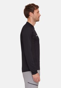 Langärmliges Shirt aus schwarzem Stretchstoff, mit Rundhalsausschnitt, figurbetontem Schnitt und dezentem Logodetail auf der Brust.