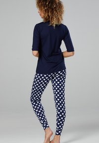 Navy top with three-quarter sleeves paired with fitted leggings featuring a white heart pattern on a dark background. Smooth texture.