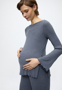 Γκρι ριμπ τοπ εγκυμοσύνης με μακριά φαρδιά μανίκια, άνετη εφαρμογή και βολάν στο τελείωμα, σετ με αντίστοιχο ριμπ παντελόνι. Απαλή υφή.