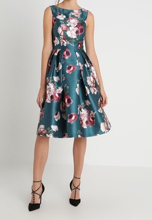 Türkisfarbenes Satin-Kleid mit floralem Muster, ärmelloses Design, ausgestellter Rock und schulterlangem Saum. Schwarze, Riemchen-Hochzeitschuhe sind enthalten.