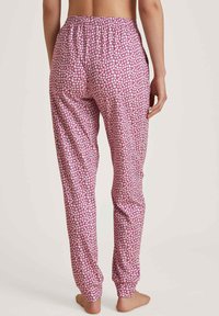 Roze pyjamabroek met een klein bloemenpatroon, elastische tailleband en taps toelopende broekspijpen. Gemaakt van zachte stof, met een lichte en ademende textuur.
