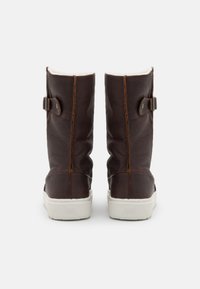 Brown leather boots with a textured finish, featuring a white rubber sole and side buckle detail. No visible patterns. Back view.