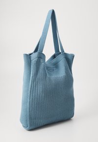 Blauwe gebreide tote bag met verticale ribbelstructuur, voorzien van twee stevige handvatten en een open bovenkant voor gemakkelijke toegang.