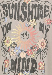 Graues T-Shirt mit großer, schwarzer, abgewetzter Schrift "SUNSHINE ON MY MIND", umgeben von bunten Blumen und einer lächelnden Sonnengrafik.