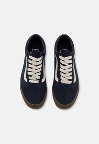 Mørkeblå mockasinsneakers med kremfargede snører og sideakenter. Rund tåform og teksturert overdel for bedre grep. Brun gummisåle.