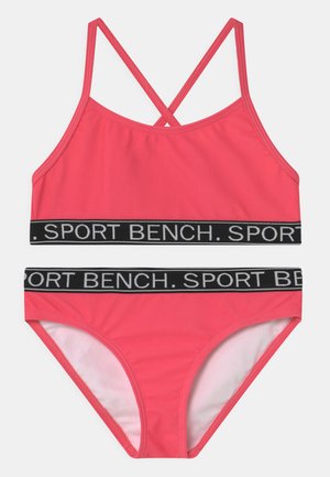 Rosa Sport-Bikini-Set mit einem kreuzend verlaufenden Trägerdesign, schwarzem Gummiband mit "SPORT BENCH"-Schriftzug und glatter Textur.