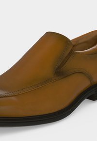 Chaussure habillée en cuir marron à enfiler avec semelle noire et coutures discrètes.