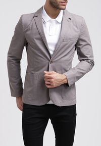 Jasnoszary dopasowany żakiet wykonany z gładkiego materiału, z klapami, jedną kieszenią na piersi i dwiema kieszeniami z przodu. Slim fit.