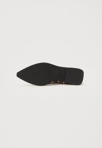 Suela de zapato negro de tacón con forma puntiaguda. Presenta un acabado texturizado y un acento de estampado de leopardo visible en el lateral.