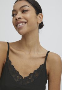 Zwarte tanktop met een V-halslijn afgewerkt met kant. Glad textuur, verstelbare banden en een aansluitend ontwerp. Geen extra patronen of accenten.