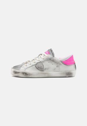 Gray leather sneaker with pink accents, textured finish, rounded toe, and lace-up design. Scuffed sole and branding on the heel.