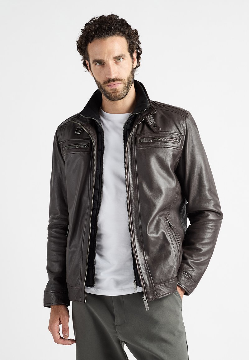 Bruine leren jas met een opstaande kraag, rits aan de voorkant en meerdere ritszakken. Glad van textuur met een subtiele glans en een op maat gemaakte pasvorm.