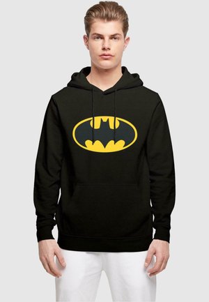 Sudadera negra con un gran logo amarillo de Batman en el pecho. Cuenta con un bolsillo frontal y cordones ajustables en la capucha. Textura de tela suave.