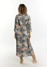 Kimono largo y estampado en tejido suave que presenta una mezcla de tonos azules, naranjas y neutros, con mangas amplias y un detalle de cintura atada.