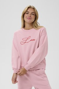 Roza dukserica iz mehkega materiala z dolgimi rokavi in elastičnimi manšetami. Spredaj je okrašena z rdečim vezenim napisom "Love". Ujemajoče hlače dopolnjujejo stilsko podobo.