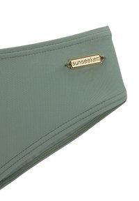 Grüner Stoffhaarband mit glatter Textur und goldfarbener "Sunseeker"-Logoplatte. Verfügt über gestickte Kanten und ein konturiertes Design.