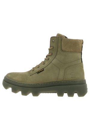 Bottes chelsea en cuir vert olive avec une finition texturée, à bout rond, à lacets à l'avant et avec une semelle en caoutchouc épaisse dotée de rainures proéminentes.