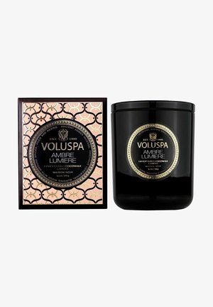 Sort lys i en blank beholder med en guld label. Kommer i en pink æske med et gentagende mønster og prægede guldaccenter.