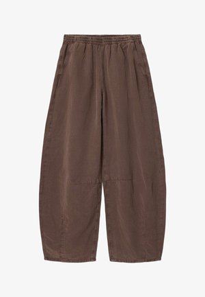 Luźne brązowe spodnie z elastycznym pasem i bocznymi kieszeniami, z przeszyciami na kolanach i szerokimi nogawkami.