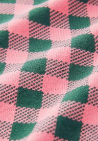 Material tricotat cu un model în carouri roz și verde, având texturi variate, inclusiv pătrate simplu colorate și cu buline, creând o adâncime vizuală.