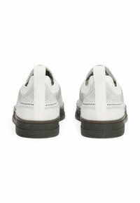 Zapatillas de malla blancas con un diseño de perfil bajo; presentan una suela gris contrastante y una pestaña en la parte posterior con "TOMMY JEANS" en relieve.