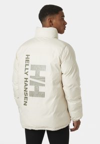 Bílá péřová bunda má vysoký límec, elastické manžety a velké šedé logo na zadní straně. Hladká, matná textura.