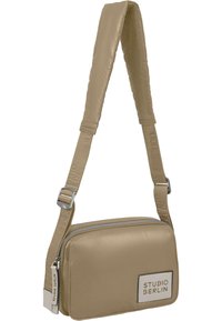 Tan crossbody taske lavet af glat stof, med en lynlåslomme, justerbar rem og et logo-patch på forsiden.