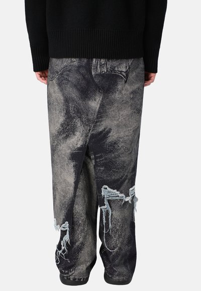Schwarze und graue, verwaschene Denim-Jeans mit lockerer Passform, die fransige Säume und ein einzigartiges Split-Design auf der Rückseite aufweisen.