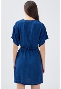 Džínové šaty, krátké rukávy, stažený pas s páskem, tmavě modrá barva, hladká textura, kulatý výstřih, ke kolenům, volnočasový design.