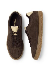 Ζευγάρι σκούρα καφέ sneakers από σουέτ με μπεζ λεπτομέρειες, υφασμένα ανοιχτό καφέ πέλματα και μαύρα κορδόνια, εμφανιζόμενα από πάνω και από το πλάι.