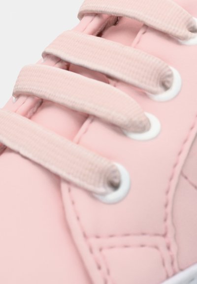 Jasnoróżowe sneakersy z teksturowanej syntetycznej cholewki, białymi oczkami i pasującymi płaskimi sznurówkami, z widocznymi detalami przeszycia.