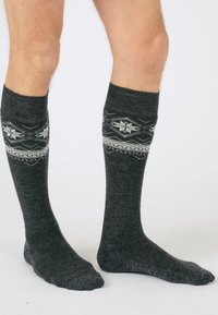 Calcetines de punto en mezcla de lana gris oscuro, con un patrón geométrico blanco cerca del puño, y una parte del pie en gris oscuro sólido y textura suave.