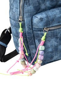 Zaino in denim blu con tasche con zip. Presenta accenti di perline colorate sui cursori. Tessuto testurizzato con motivo a griglia cucito.