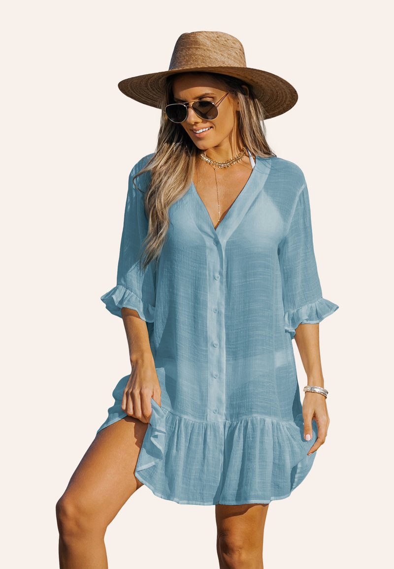 Robe chemise bleu clair à boutons, en tissu doux et texturé, avec des manches retroussées et un ourlet volanté.