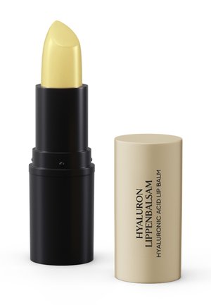 Gelber Lippenbalsam-Stift in einer schwarzen Hülse mit beiger Kappe, beschriftet mit "Hyaluron Lippenbalsam Hyaluronic Acid Lip Balm."